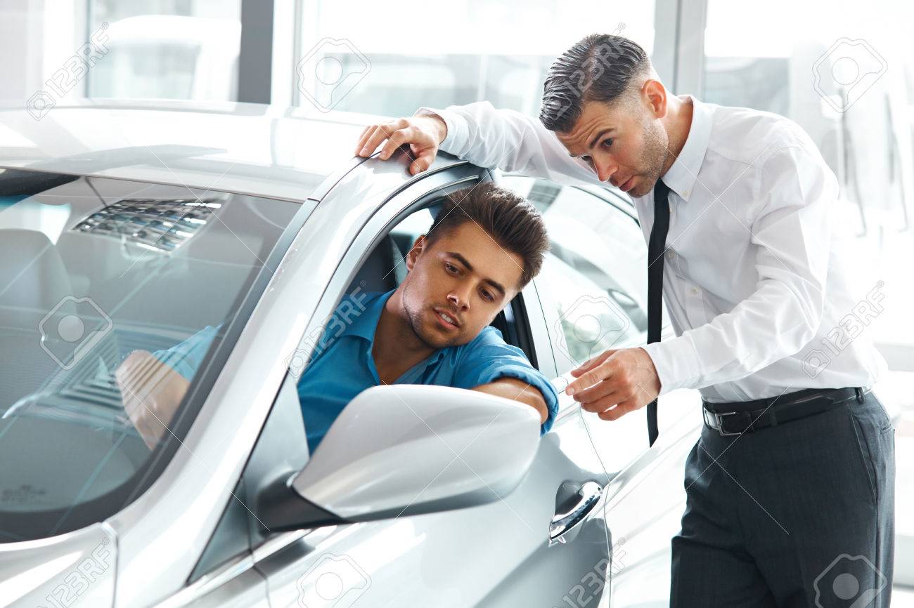 Car Sales Consultant Showing a New Car to a Potential Buyer in S